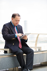 Image showing Senior Asian businessman in suit using tablet PC