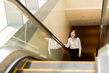 Image showing Young Asian female executive going up escalator