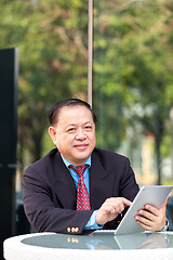 Image showing Senior Asian businessman in suit using tablet PC