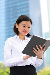 Image showing Young Asian female executive reading book smiling portrait