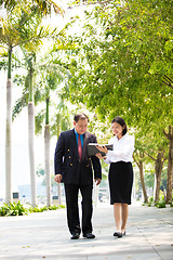 Image showing Young Asian female executive and senior businessman walking together