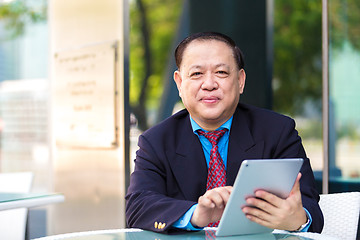 Image showing Senior Asian businessman in suit using tablet PC