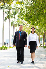 Image showing Young Asian female executive and senior businessman walking together