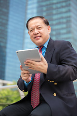 Image showing Senior Asian businessman in suit using tablet PC