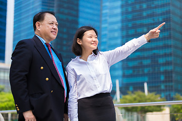 Image showing Senior businessman and young female executive pointing at a direction