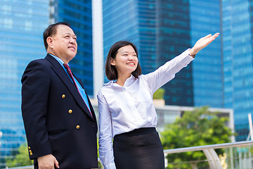 Image showing Senior businessman and young female executive pointing at a direction