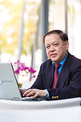 Image showing Senior Asian businessman in suit using laptop PC