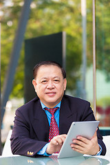 Image showing Senior Asian businessman in suit using tablet PC