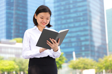 Image showing Young Asian female executive reading book smiling portrait