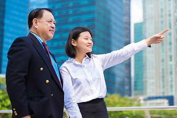 Image showing Senior businessman and young female executive pointing at a direction