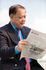 Image showing Senior businessman in suit reading newspaper