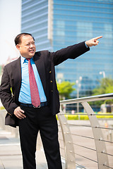 Image showing Senior businessman in suit pointing at a direction