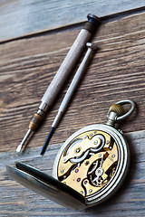 Image showing reverse side of the vintage pocket watch and a screwdriver