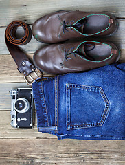 Image showing Still life with blue jeans, brown boots, leather belt and camera