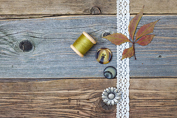 Image showing lace ribbon, vintage buttons, spools of thread and dry leaves