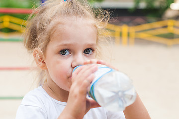 Image showing Three year old girl drinks from a bottle