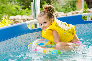 Image showing Cheerful girl bathing trying to get into the swimming circle