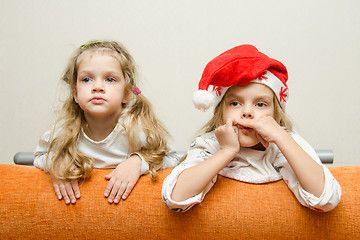 Image showing Two girls looking to left leaning back on the couch