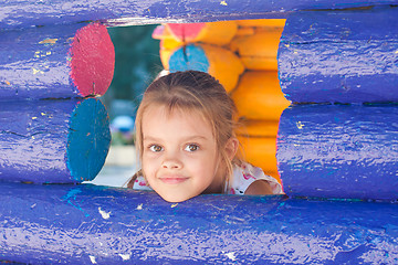 Image showing Five-year girl looks out from a wooden window