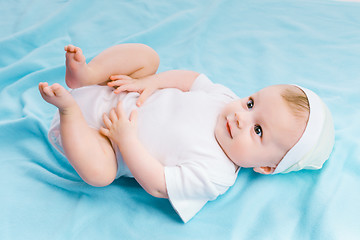 Image showing baby in hat lying on a blue blanket