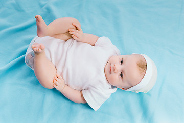 Image showing baby in hat lying on a blue blanket