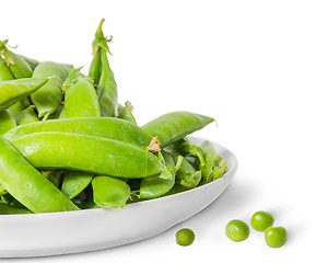 Image showing Closeup pile of green peas in pods in white plate