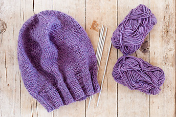 Image showing wool purple hat, knitting needles and yarn 