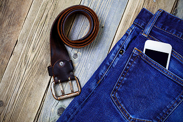 Image showing old blue jeans, vintage leather belt and smartphone