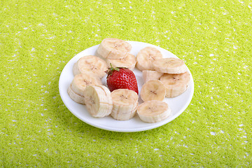 Image showing Bunch of bananas and several strawberries on white plate