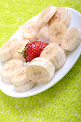 Image showing Bunch of bananas and several strawberries on white plate