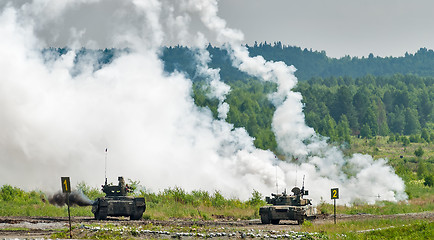 Image showing Military tanks hide behind smoke screen