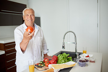 Image showing man cooking at home preparing salad in kitchen