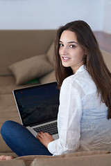 Image showing relaxed young woman at home working on laptop computer