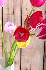 Image showing Bouquet of red tulips against a wooden background, close up flowers