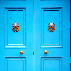 Image showing  blue handle in london antique brown door  rusty  brass nail and