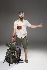 Image showing Male tourist with backpack hitchhiking on gray background