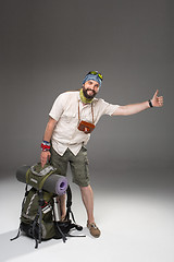 Image showing Male tourist with backpack hitchhiking on gray background