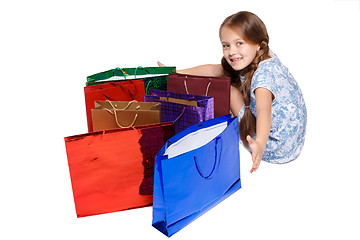 Image showing Happy girl with shopping bags sitting at studio 