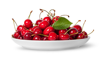 Image showing Pile of sweet cherries with leaf on white plate