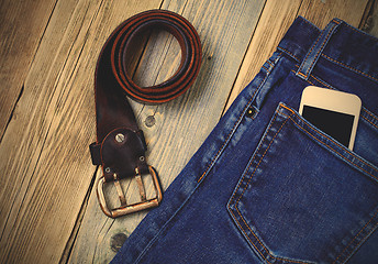 Image showing old blue jeans, vintage leather belt and smartphone