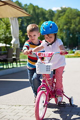 Image showing Boy and girl in park learning to ride a bike