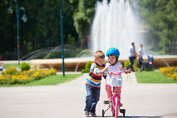 Image showing Boy and girl in park learning to ride a bike