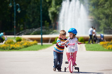 Image showing Boy and girl in park learning to ride a bike