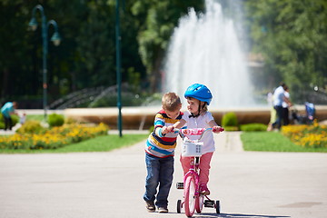 Image showing Boy and girl in park learning to ride a bike