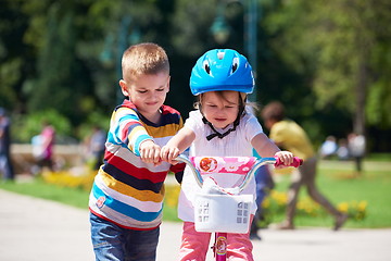 Image showing Boy and girl in park learning to ride a bike