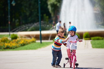 Image showing Boy and girl in park learning to ride a bike