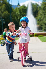 Image showing Boy and girl in park learning to ride a bike