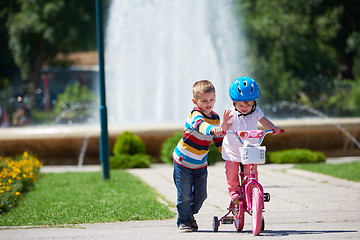 Image showing Boy and girl in park learning to ride a bike