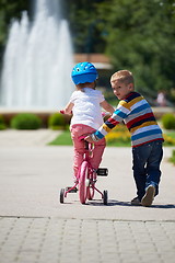 Image showing Boy and girl in park learning to ride a bike