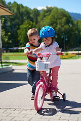 Image showing Boy and girl in park learning to ride a bike